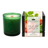 A green glass scented candle with a wooden wick stands next to its black retail box. The box features a label with the brand 'Noble Crown Fragrances' and the scent name 'Pico de Gallo', along with illustrations of tomato and cilantro.