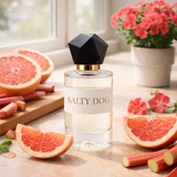 Perfume bottle labeled 'Salty Dog' on a table with grapefruit slices and flowers.