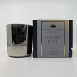 A silver candle labeled 'Snow Day' by Nobble Crown Fragrances, along with its packaging box with the same label.